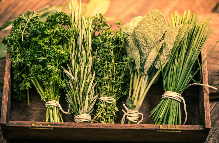 five bundles of herbs tied with string in wooden box